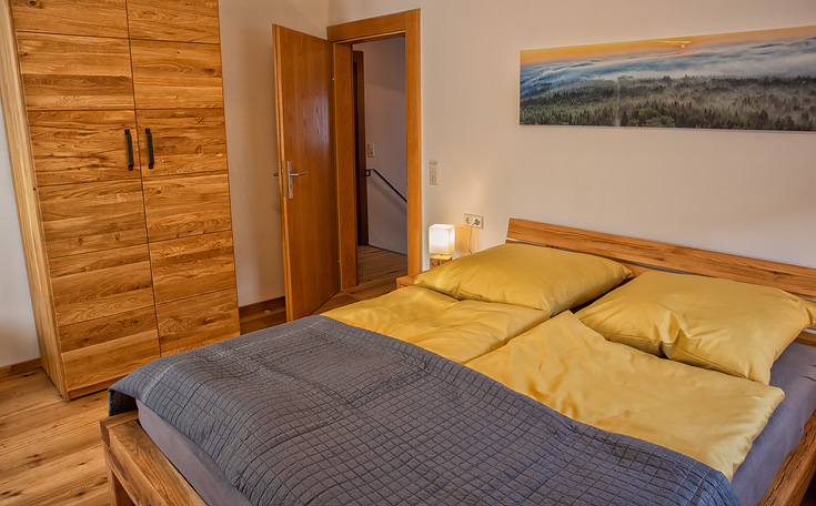 Ferienhaus Enztalblick in Enzklösterle im Nordschwarzwald - Das Schlafzimmer im Obergeschoss mit Schrank und Bett aus massivem Eichenholz